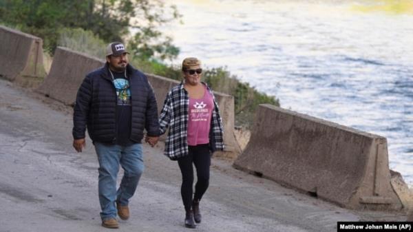 Molli Myers and her husband, Frankie, hold hands on Aug. 28, 2024, as they watch crews work to remove the final cofferdam that was left of Iron Gate Dam, allowing the Klamath River to flow through near Hornbrook, California. (Matthew Johan Mais via AP)