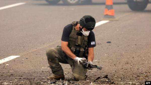 A member of Israeli security forces inspects the impact site of a reported rocket fired from Lebanon, on the Horeshim interchange in central Israel on October 1, 2024.