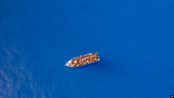 FILE - A group thought to be migrants from Tunisia on board a precarious wooden boat waits to be assisted by a team of the Spanish NGO Open Arms, around 20 miles southwest from the Italian island of Lampedusa, July 29, 2021. 