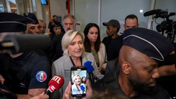 French far-right leader Marine Le Pen is flanked by police officers as she arrives at the court house in Paris, Sept. 30, 2024. 