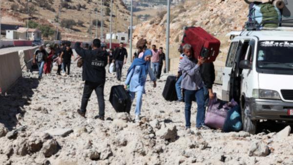 People carry their belo<em></em>ngings while walking on the rubble, after an Israeli strike, as they flee Lebanon due to o<em></em>ngoing hostilities between Hezbollah and Israeli forces, at Masnaa border crossing with Syria, in Lebanon, October 4, 2024. REUTERS/Mohamed Azakir

