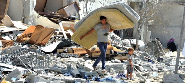 A Palestinian man salvages items from the rubble of his home destroyed by Israeli strikes on a building in northern Gaza Strip in 2014. (file)