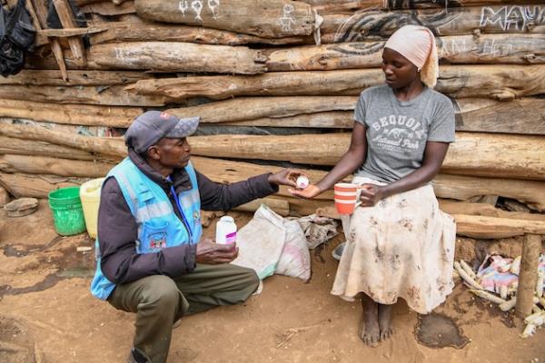 173759-Pascal, a Community Drug Distributor (CDD), hands azithromycin tablets to Abedi during a Mass Drug Administration (MDA) in Kajaido, near the Kenyan-Tanzania border. Credit: Sightsavers/Samuel Otieno