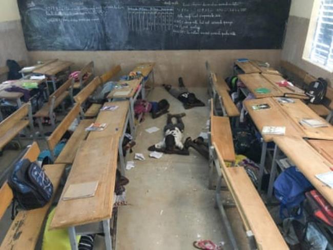 Children hide under desks in a classroom