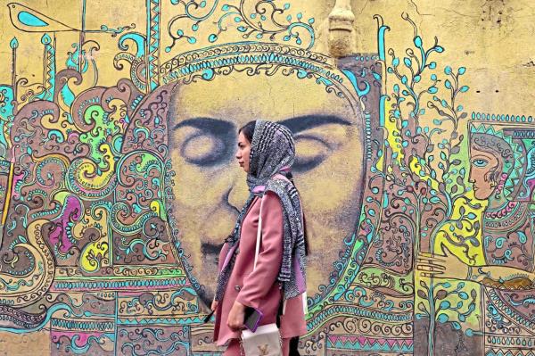 A woman walks past a neighbourhood mural painted by Yazdi. Photo: AFP